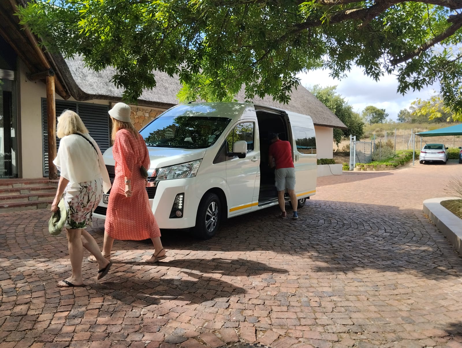 Guests walking to a Stellenbosch Shuttles minibus at a thatched wine estate